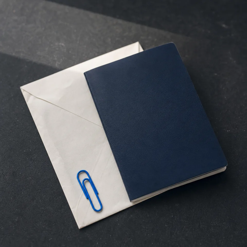 A navy passport tucked into a cream envelope with a paper clip